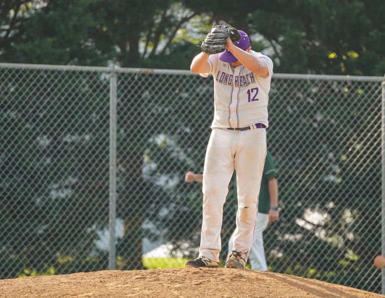A baseball player in a Long Reach uniform prepares to pitch on a sunny day.