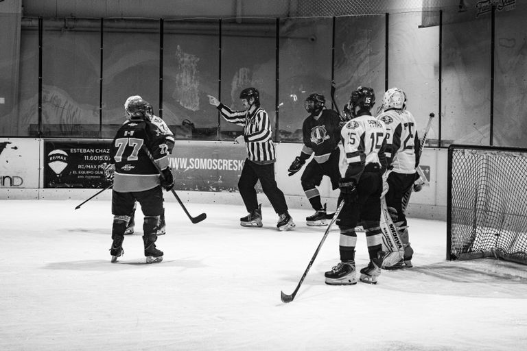 Black and white photo of an ice hockey game with players and referee in Buenos Aires.