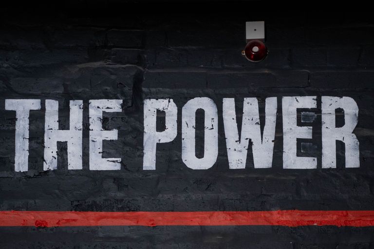 Close-up of 'The Power' graffiti on a dark wall, emphasizing strength and impact.
