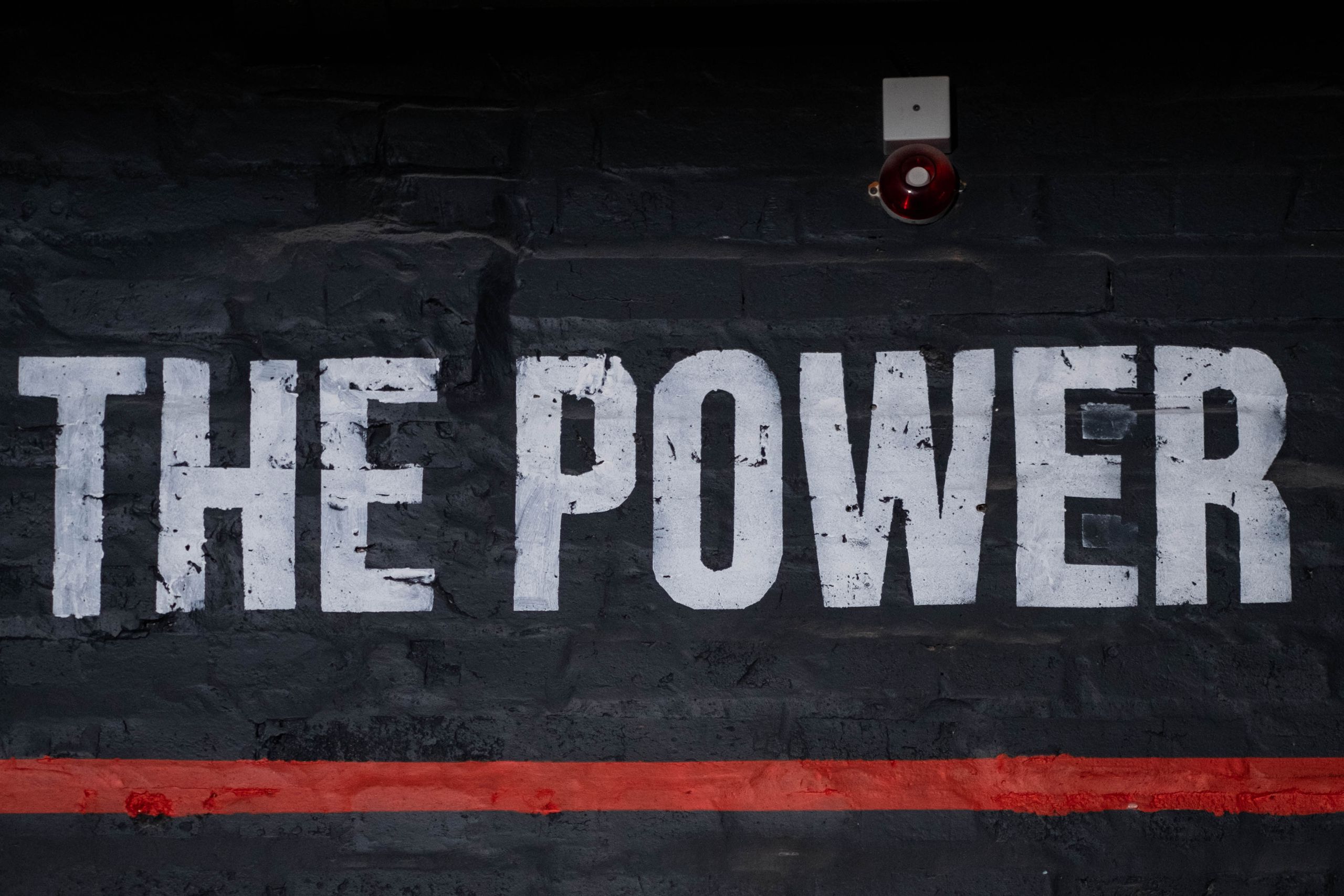 Close-up of 'The Power' graffiti on a dark wall, emphasizing strength and impact.