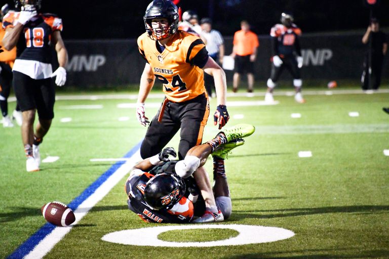 Dramatic tackle during a nighttime football game with players in action.