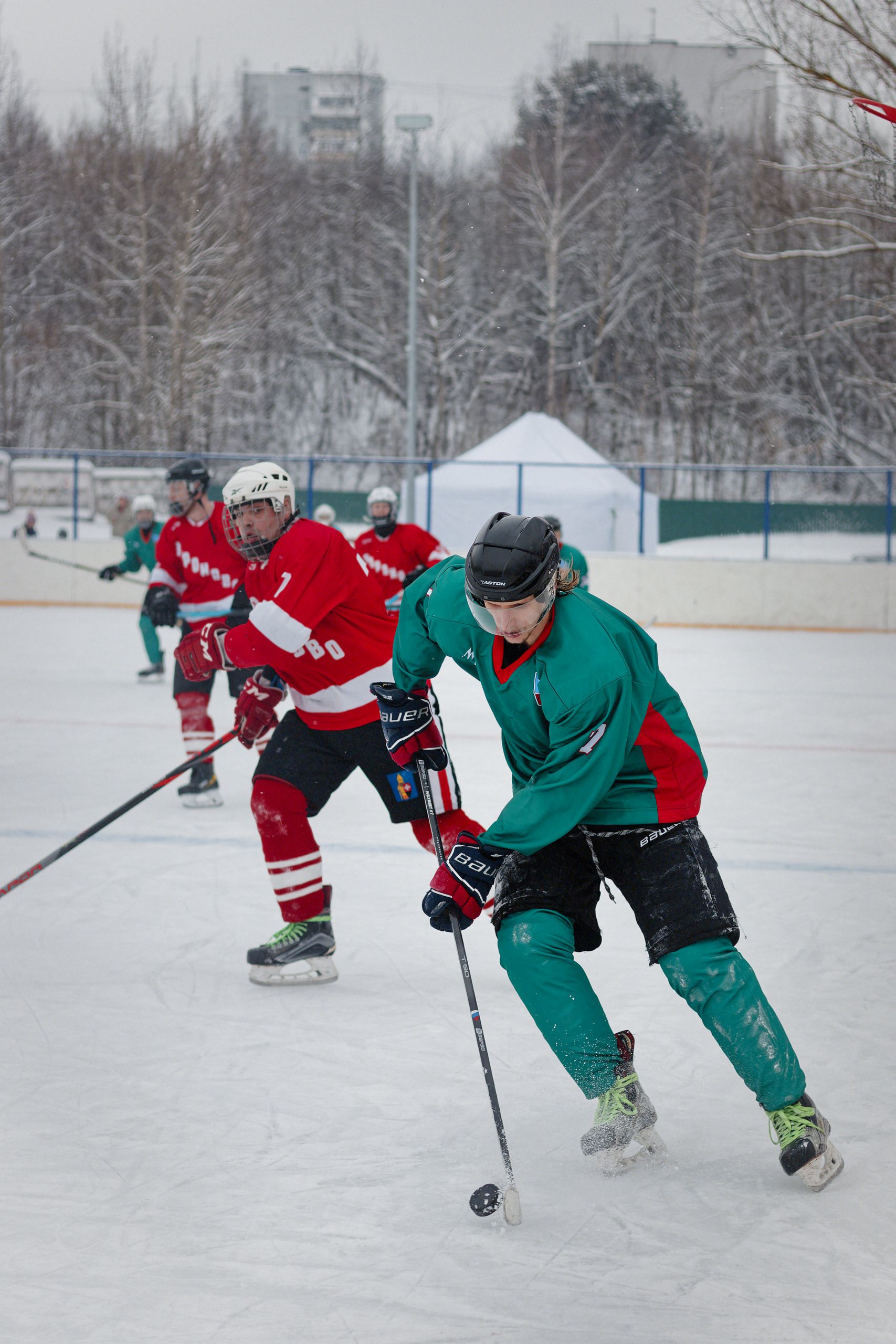 Dynamic action shot capturing an intense ice hockey match on a snowy outdoor rink.