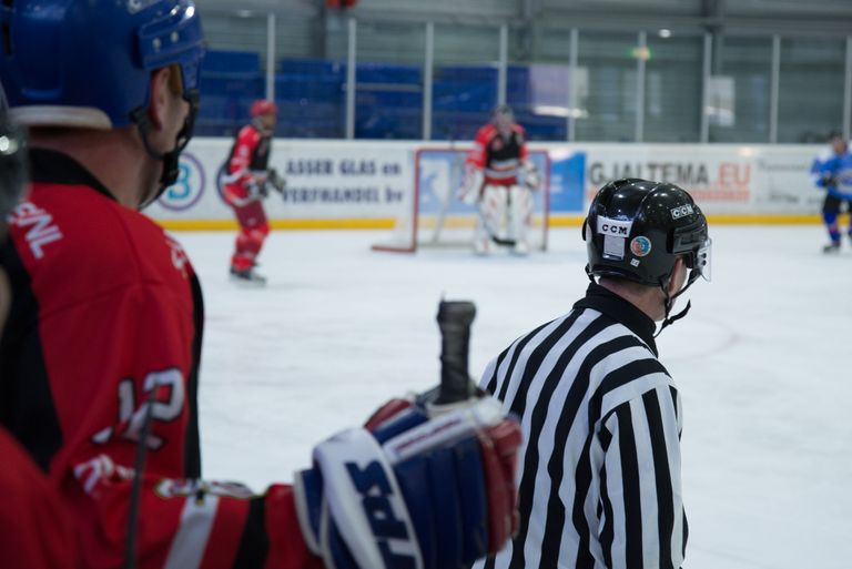 Dynamic shot of an ice hockey game with active players and attentive referee at an indoor rink.