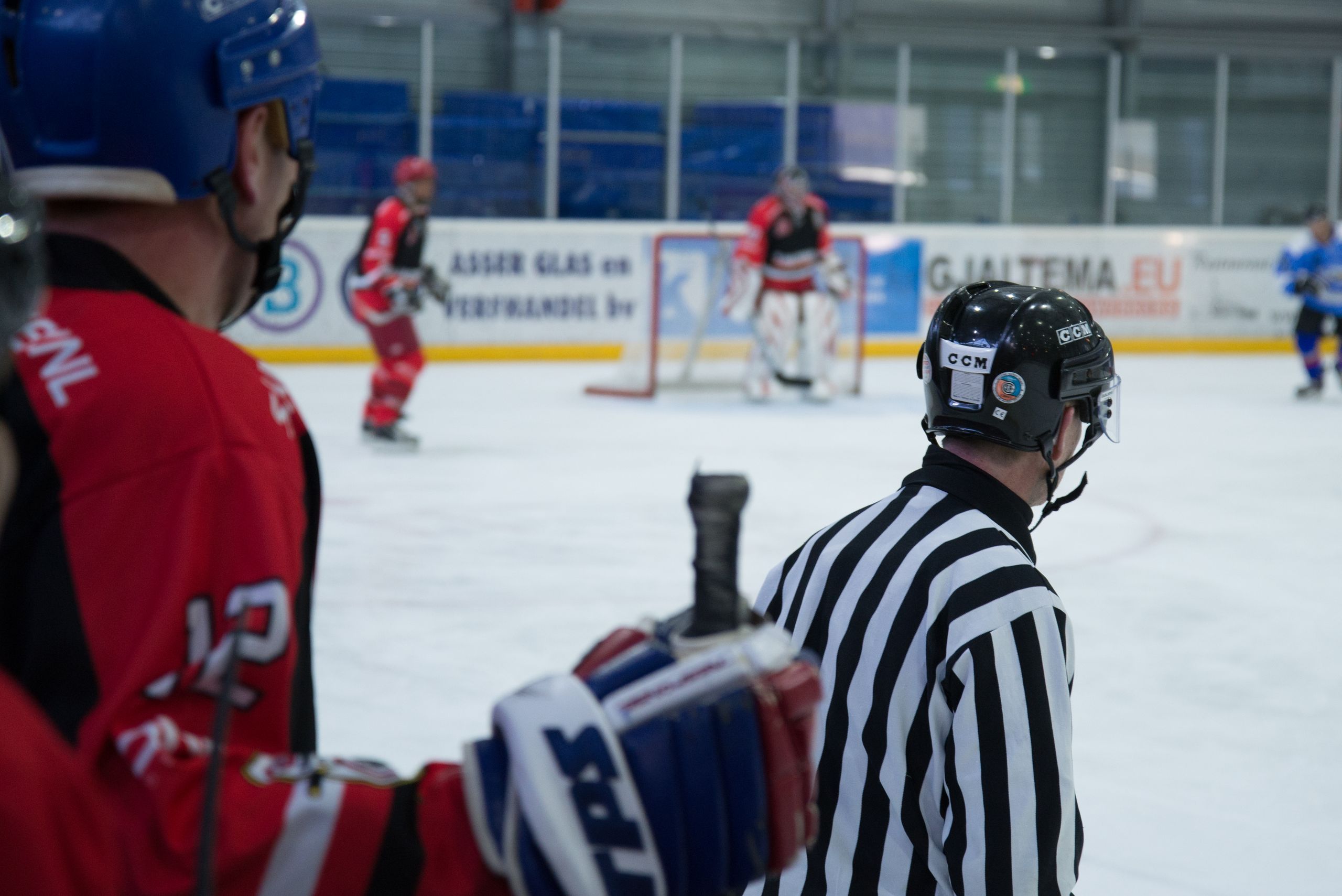 Dynamic shot of an ice hockey game with active players and attentive referee at an indoor rink.