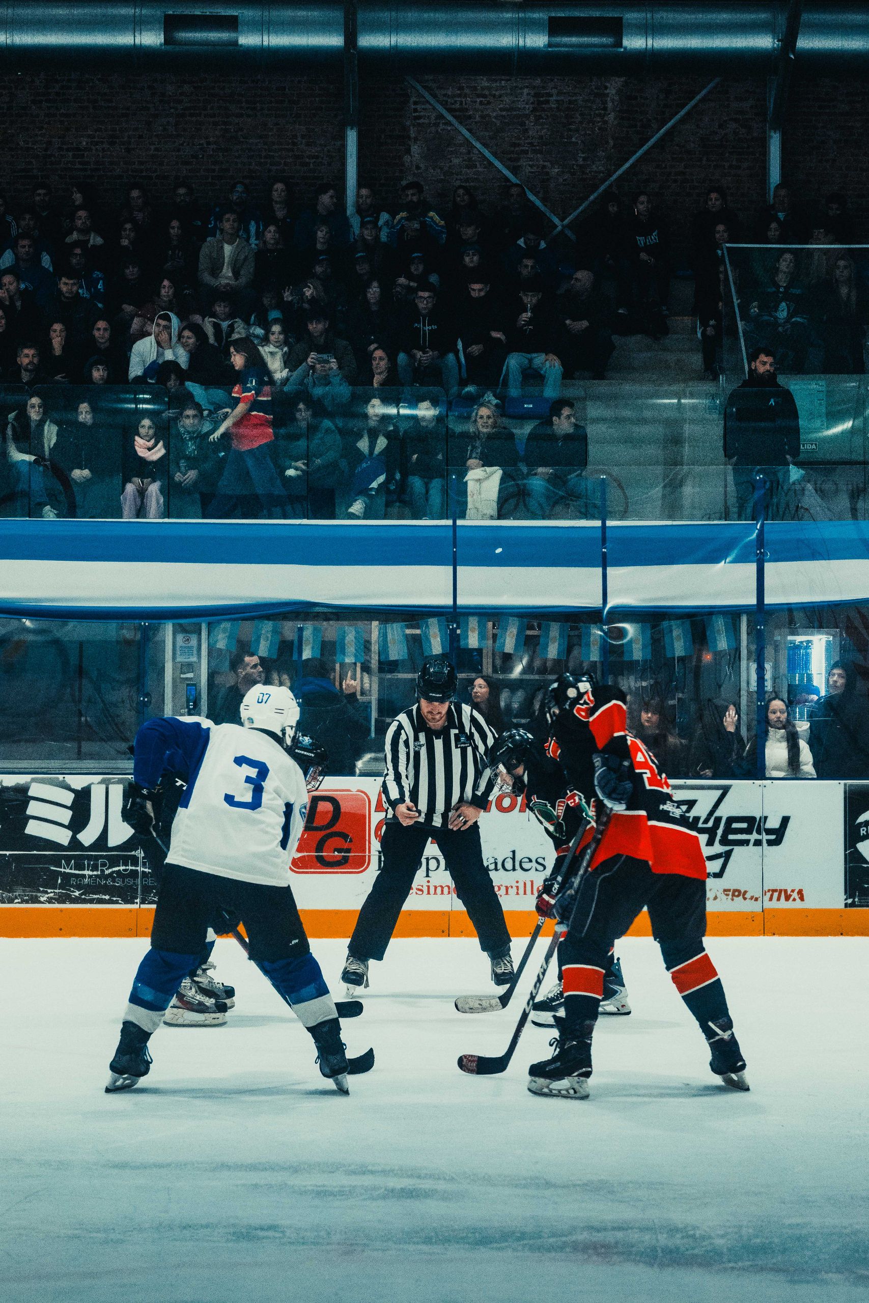 High-energy ice hockey match with players in action during face-off at Buenos Aires arena.
