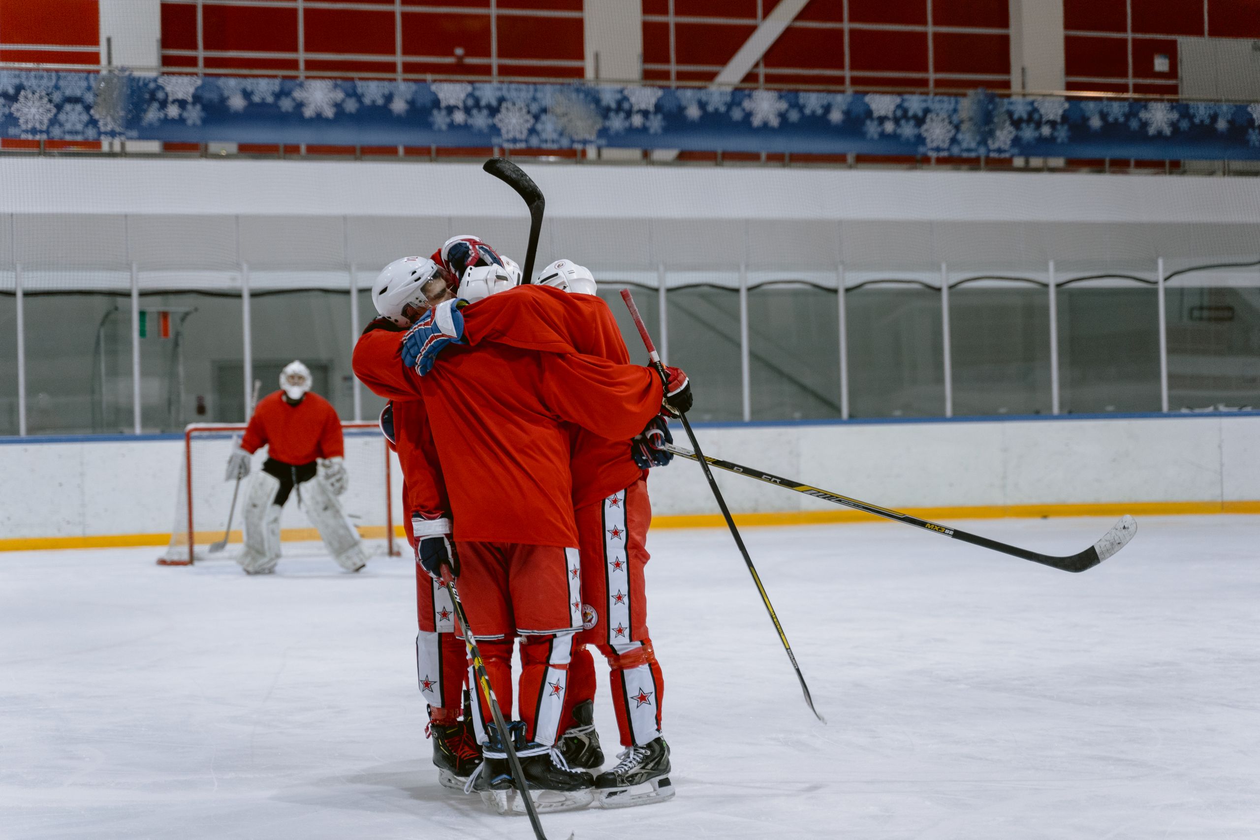 Hockey players in red uniforms embrace on ice rink after a game.